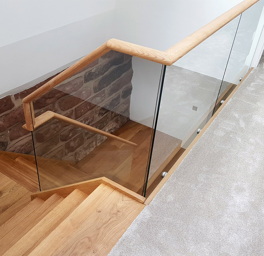 Glass balustrade with wooden handrail around a staircase