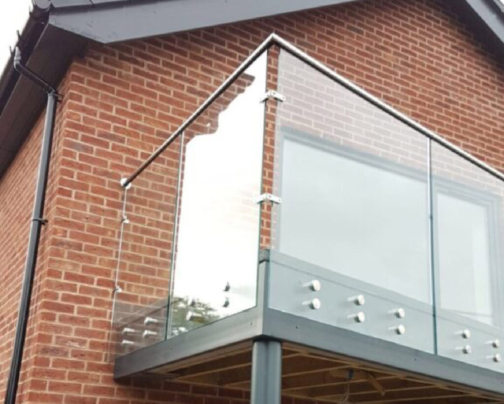 Glass balustrade sections with stainless steel rail around an upper floor balcony