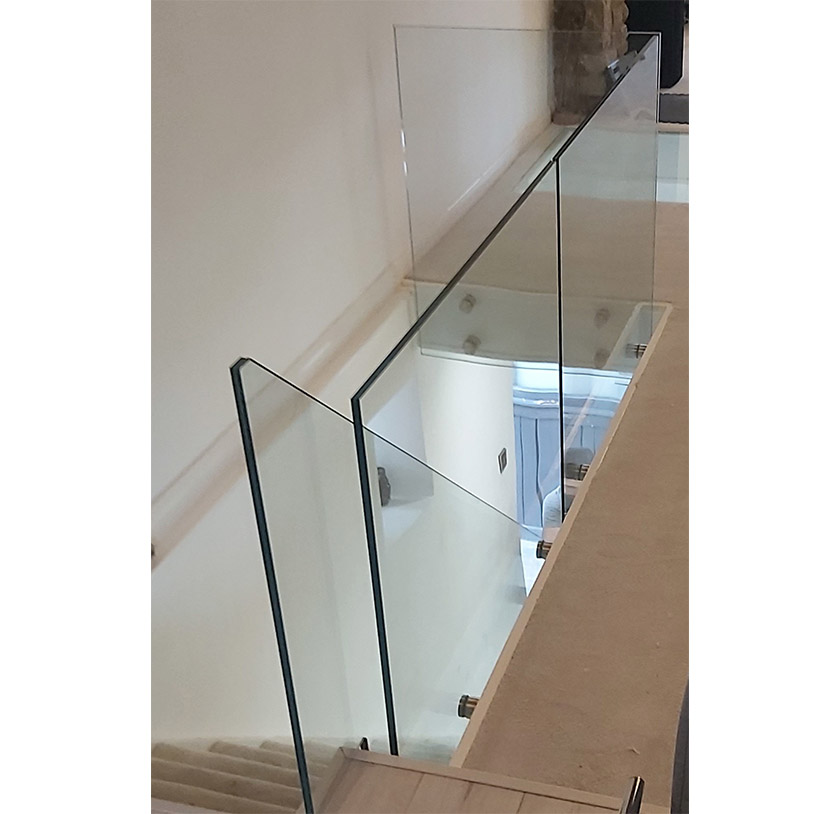 Frameless glass balustrade surround at top of a staircase