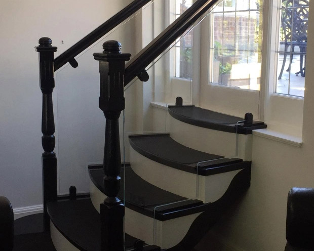Glass balustrade along short staircase with traditional wooden banister and posts