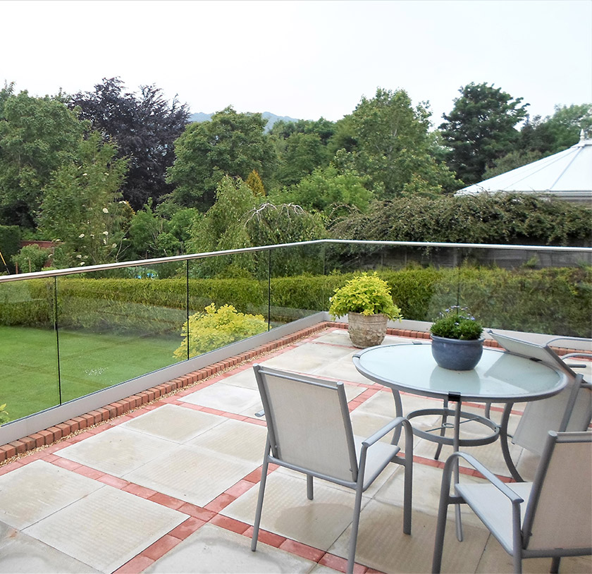 Glass balustrade with stainless steel handrail on a balcony overlooking a garden