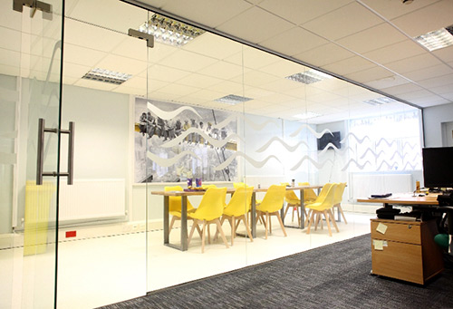 Floor to ceiling glass office partitions and door with decorative logo