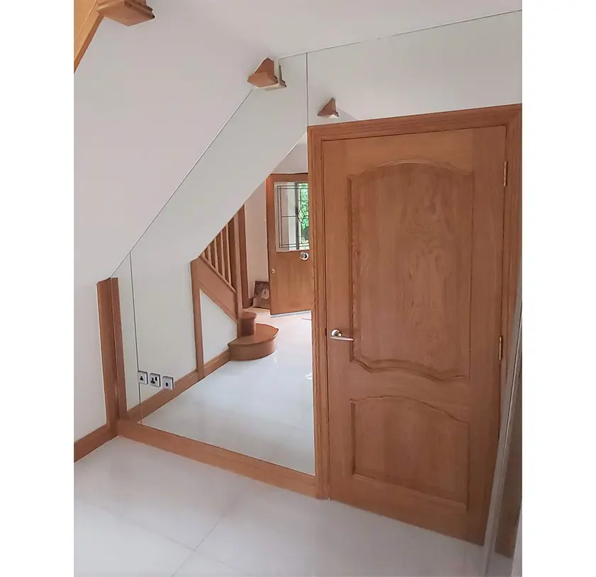 Wooden door surrounded by a mirror that is cut around the room's angles