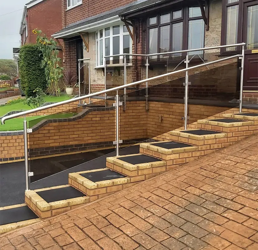 Glass balustrade with stainless steel posts on brick and tarmac steps