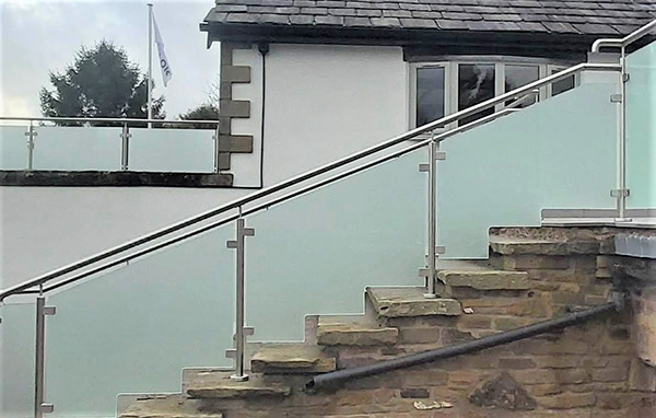 Frameless frosted glass balustrade with stainless steel posts and handrail along stone garden steps
