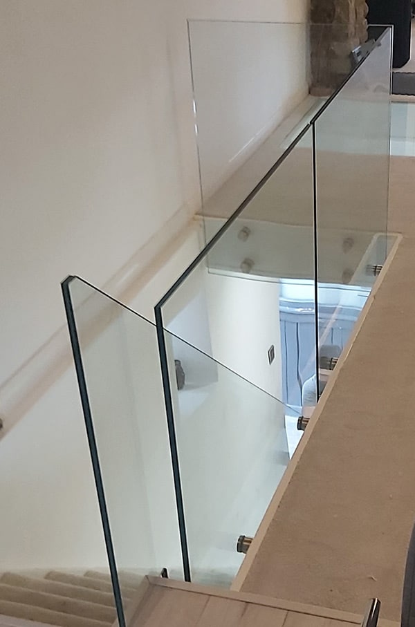 Glass balustrade and banister surround at top of a staircase