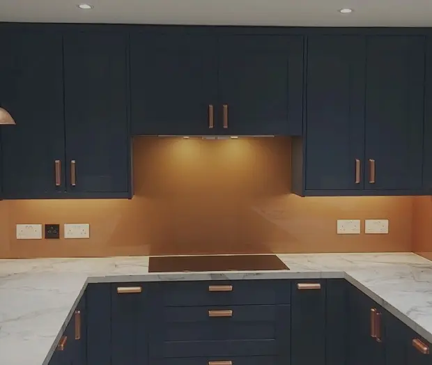 Copper coloured glass kitchen backsplash above worktops